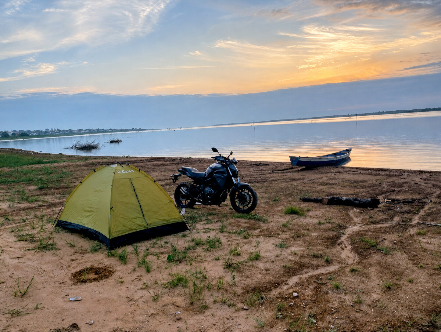 A motorcycle and tent pitched beside the Oti River at sunset