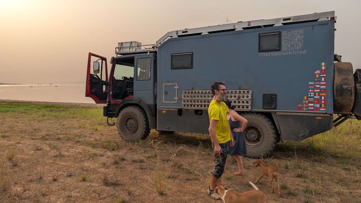 Overlanders beside their expedition truck at Dream Village by the river